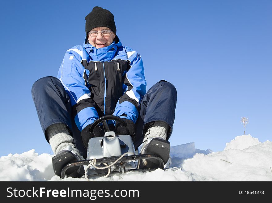 Middle-aged man sledding. Sky on background.