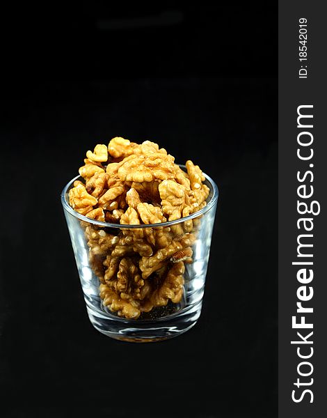 Walnut kernels in a cup on black background