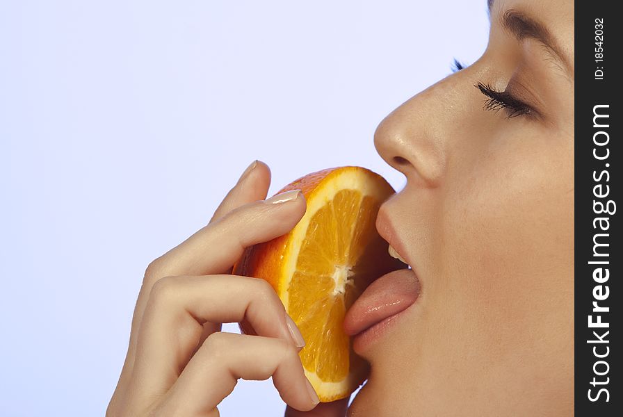 Young woman enjoying a slice of orange