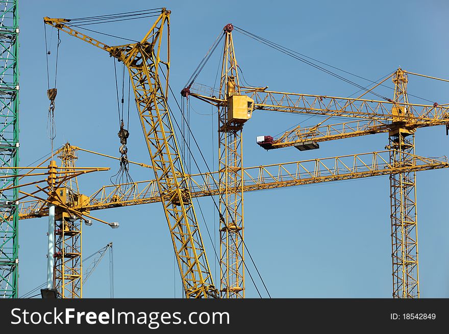 Six construction cranes over blue sky