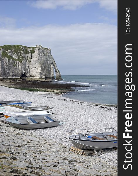 Little boats on the beach of Etretat, Normandy, France. In the back the famous white cliffs