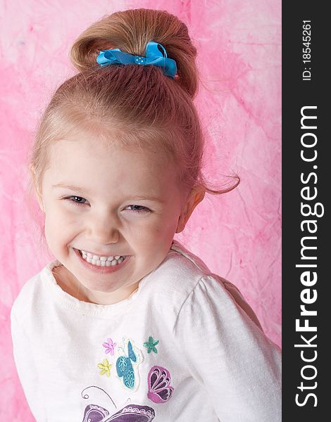 A happy but slightly shy young women. There is a pink background and she has a blue ribbon in her background. A happy but slightly shy young women. There is a pink background and she has a blue ribbon in her background.