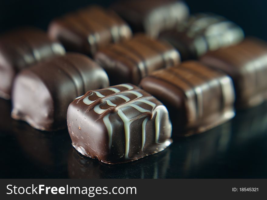 Delicious chocolates on a reflective background. The nearest one is in sharp focus.