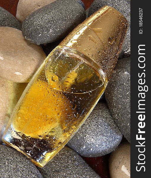 Photo of a bottle of cologne with drops of water on rocks. Photo of a bottle of cologne with drops of water on rocks