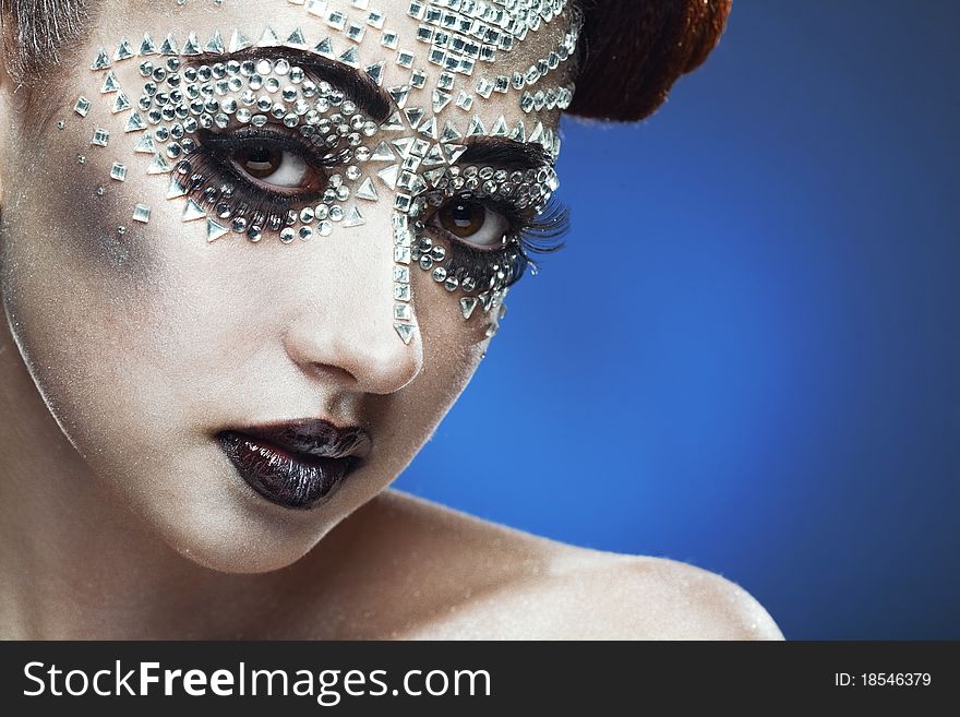 Beauty woman makeup with crystals on face on blue background