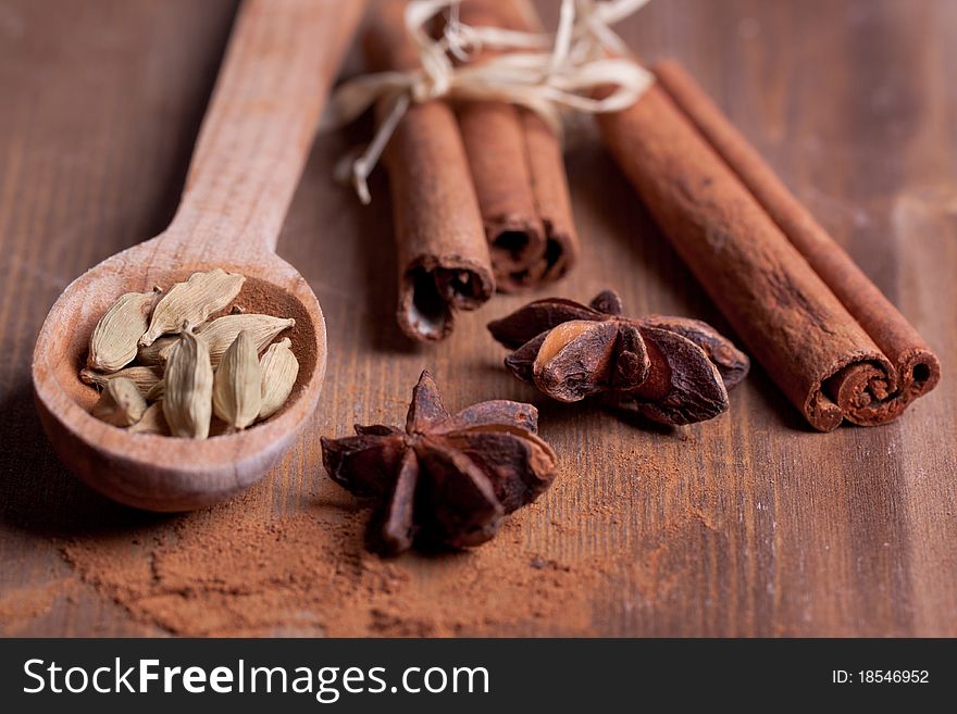 Mix of spice cinnamon, anise, cardamom in wooden spoon on wooden table