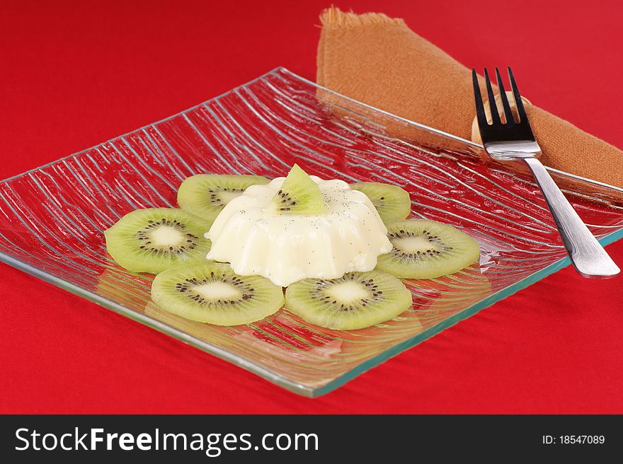 Panna cotta with kiwi slices served on a glass plate.