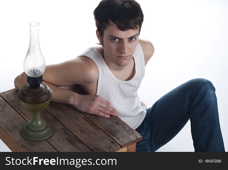 Portrait of a young man near a wooden stool and a kerosene lamp