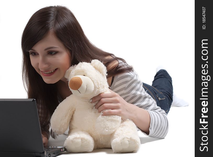 The beautiful girl embracing a teddy bear, communicates with notebook in a social network. The beautiful girl embracing a teddy bear, communicates with notebook in a social network.