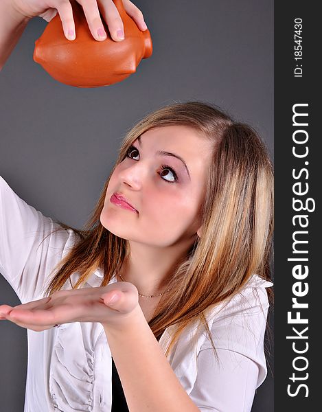 Young woman trying to get money from her piggy bank