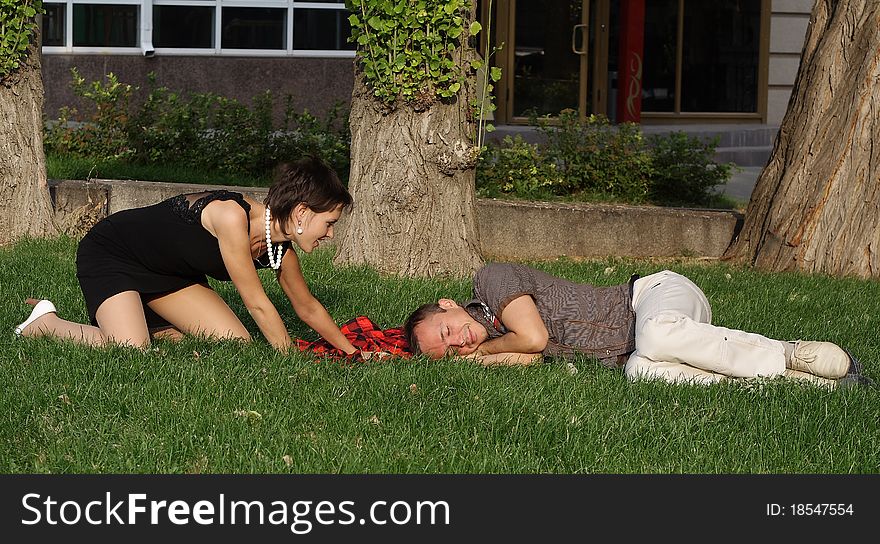The guy and the girl have a rest in park on a grass. The guy and the girl have a rest in park on a grass