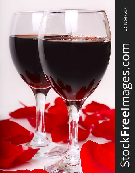 Two glasses of wine with petals of  red rose