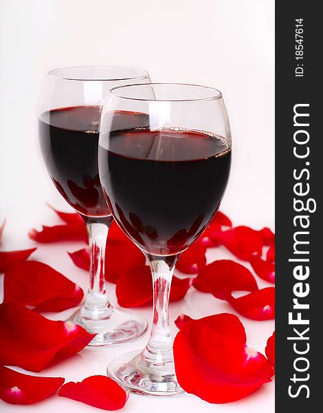 Two glasses of wine with petals of red rose