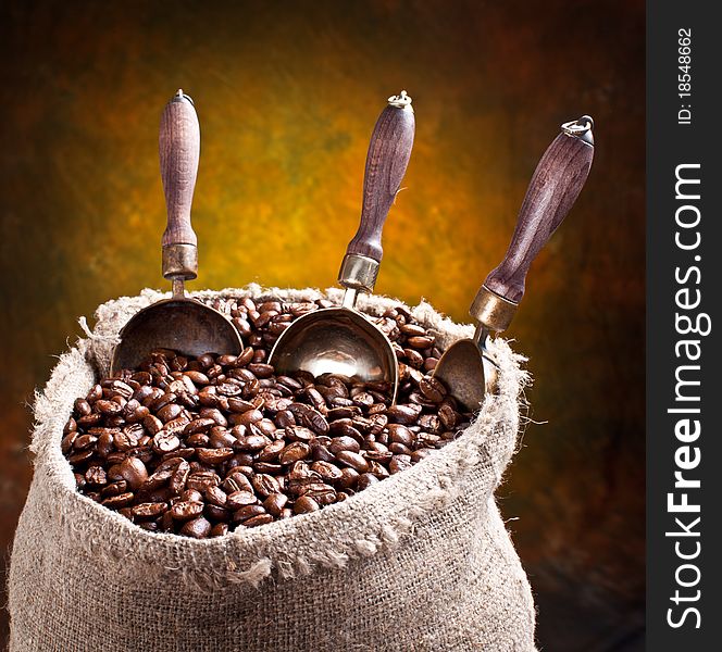 Sack of coffee beans and scoop. On a dark background.