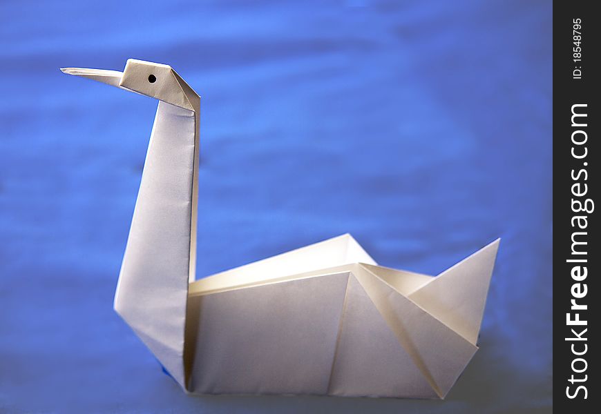 Origami white swan, made of white paper with black eyes. Origami white swan, made of white paper with black eyes