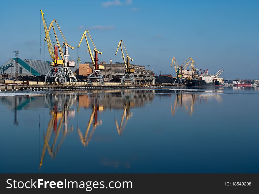 Harbor in sunshine winter day with crane reflection on water