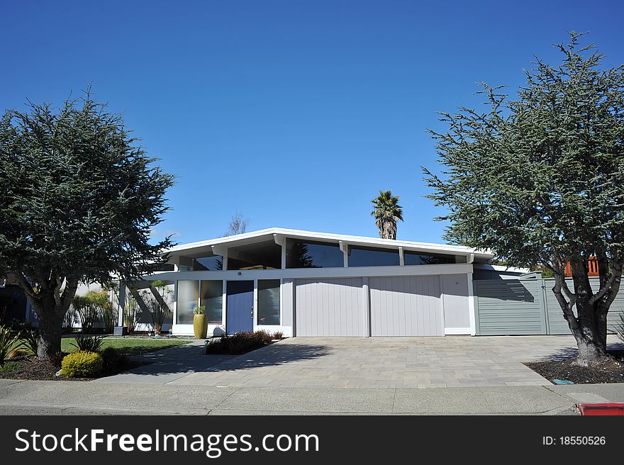 House surrounded by trees and grass with blue sky.