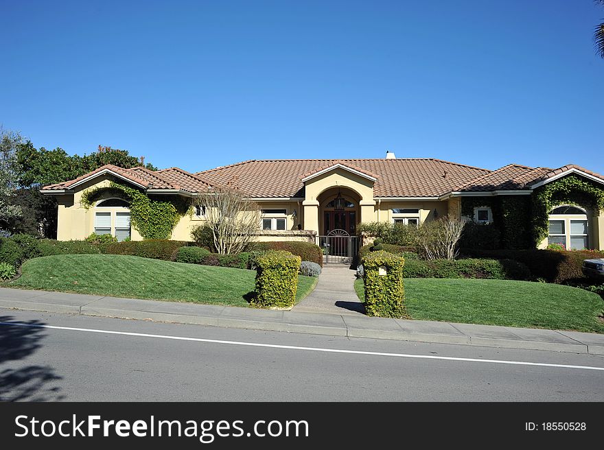 House surrounded by trees and grass with blue sky.