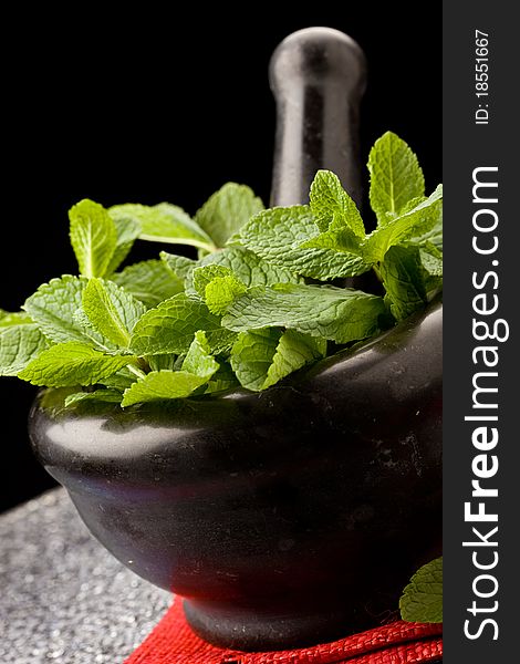 Photo of fresh aromatic mint in mortar on a glass table