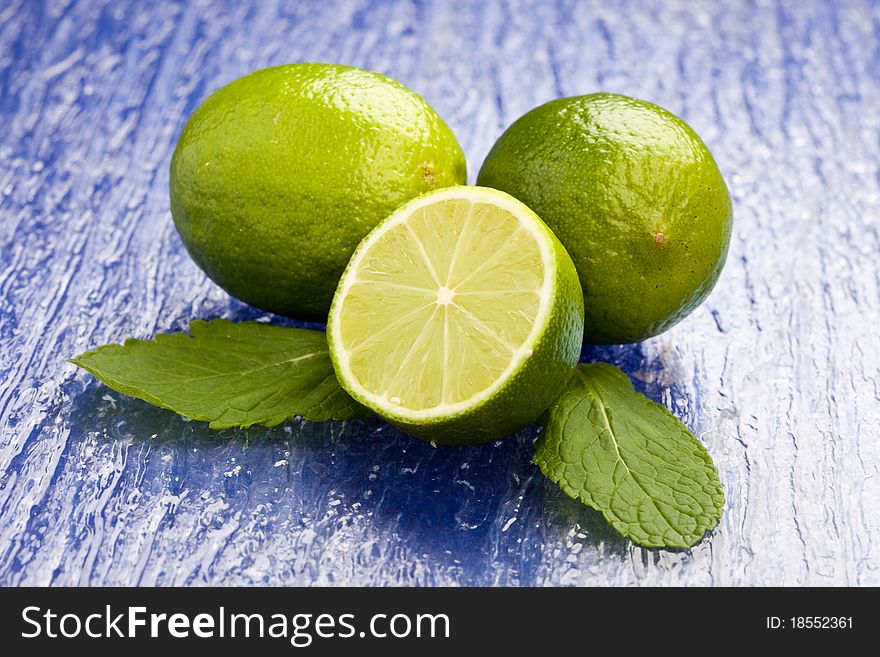 Photo of fresh lime on mint leaf putted on a blue glass table