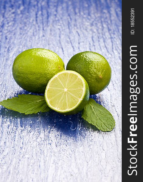 Photo of fresh lime on mint leaf putted on a blue glass table