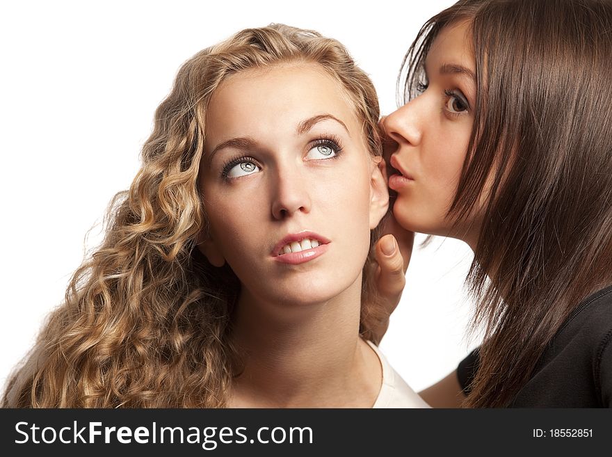 Two young girlfriends sharing their secrets, studio shot