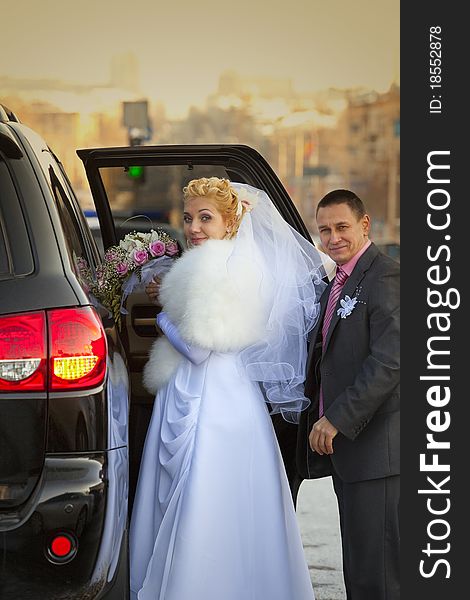 Bride and groom next to wedding car