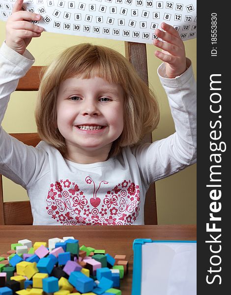 Young girl sitting at the table and playing a game. Young girl sitting at the table and playing a game.