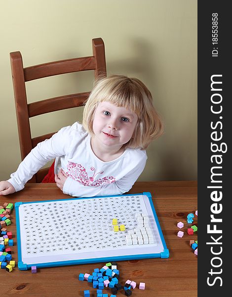 Young girl sitting at the table and playing a game. Young girl sitting at the table and playing a game.