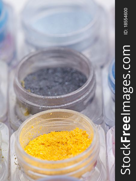 A close-up image of colorful cosmetic pigments placed in small containers. A close-up image of colorful cosmetic pigments placed in small containers