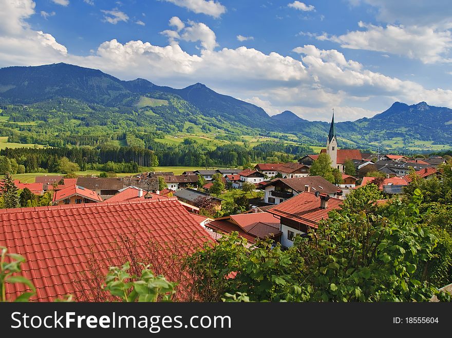Beautiful village in the valley surrounded by Alp mountains. Summer day, blue sky with clouds. Beautiful village in the valley surrounded by Alp mountains. Summer day, blue sky with clouds.