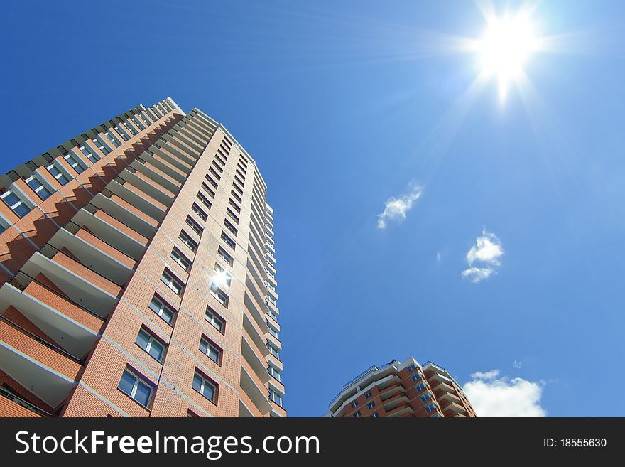 Residential highrises against vivid blue sky with sun