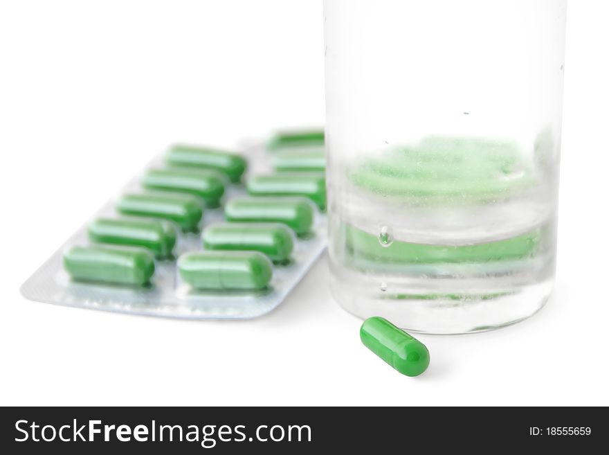 Green medical capsules and a glass of water isolated on white. Green medical capsules and a glass of water isolated on white