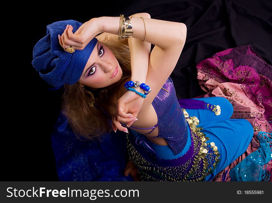 Beautiful girl in a turban and a stylized ethnic costume sits on headscarves