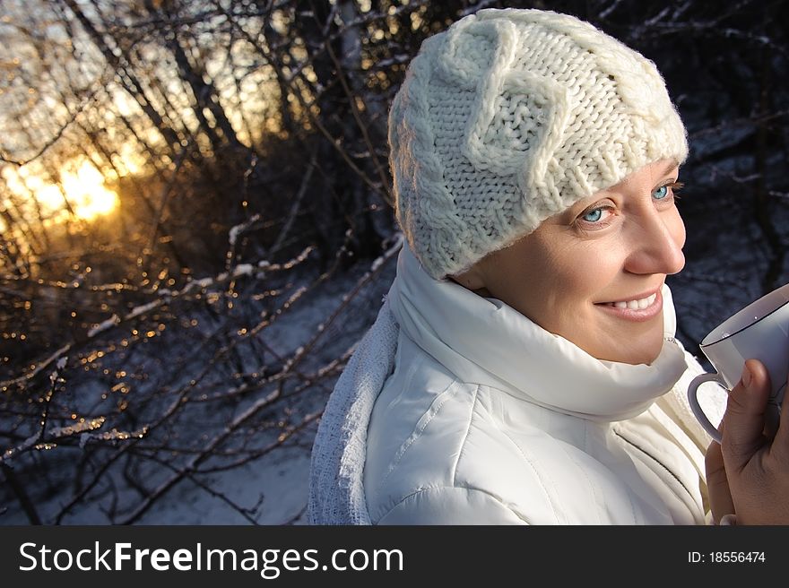Blue-eyed woman in white, with a mug in his hands, in the winter forest. closeup, portrait
