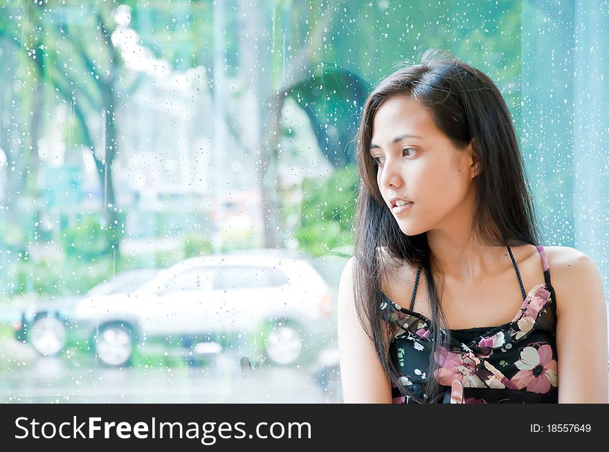 Beautiful girl is looking outside from wet window. Beautiful girl is looking outside from wet window