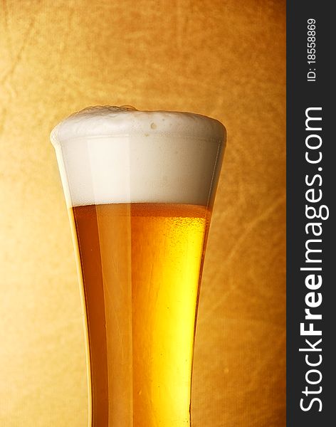 Glass of beer close-up over yellow background