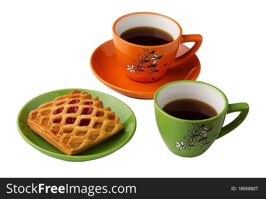 There are two cups with tea on the white background, orange and green. Also there are sweets on the saucer. There are two cups with tea on the white background, orange and green. Also there are sweets on the saucer