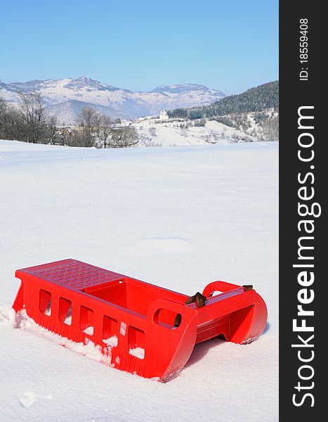 Plastic sledge with snow and mountine in background. Plastic sledge with snow and mountine in background