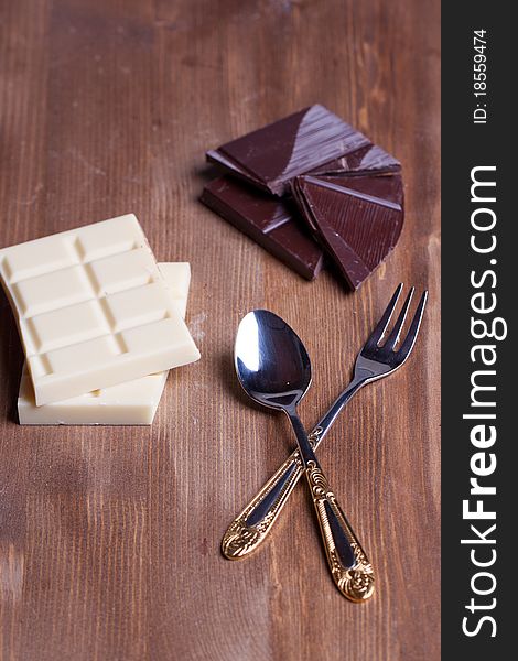 Chopped black and white chocolate with dessert service on wooden table. Chopped black and white chocolate with dessert service on wooden table