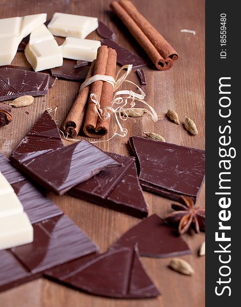 Chopped black and white chocolate with cinnamon, anise and cardamom on wooden table. Chopped black and white chocolate with cinnamon, anise and cardamom on wooden table