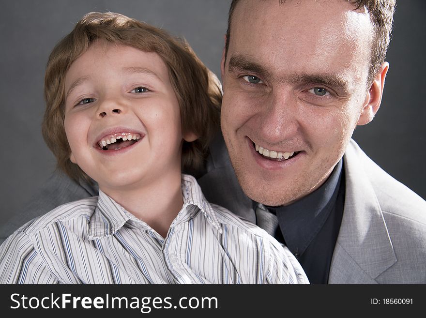Father and son cheerfully talk. On a gray background. Boy not in focus.