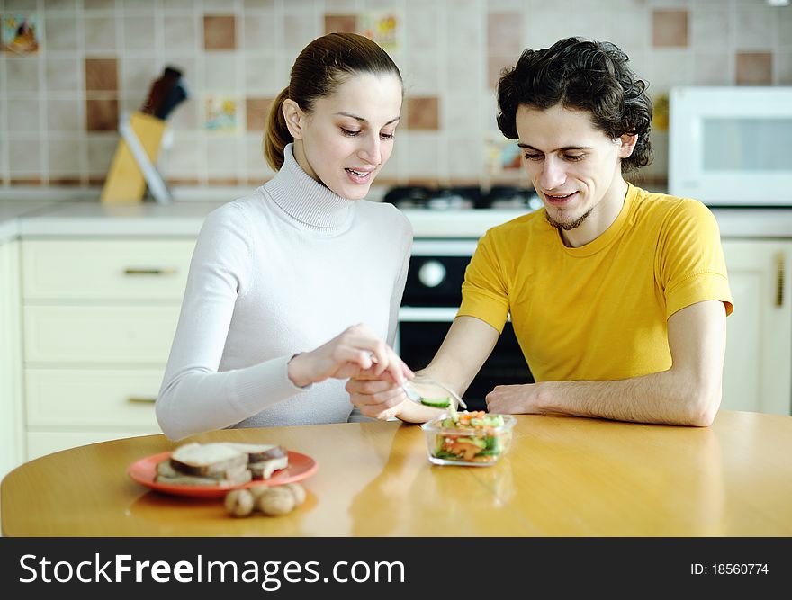 Funny scene of young happy couple playfully eating at kitchen. Funny scene of young happy couple playfully eating at kitchen