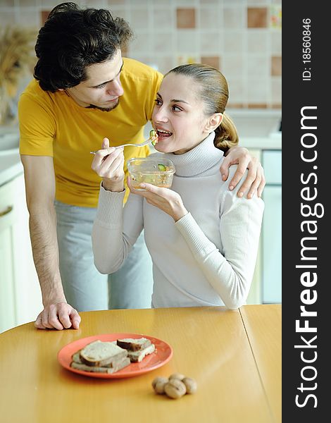An image of young couple eating at kitchen. An image of young couple eating at kitchen