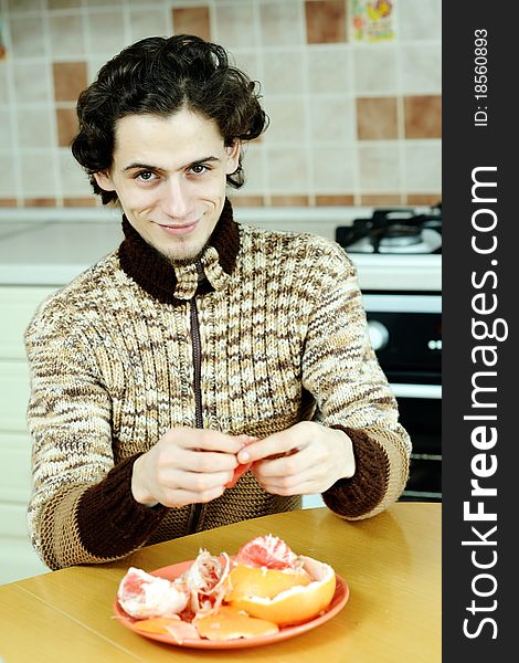 A man peelling the grapefruit in the kitchen