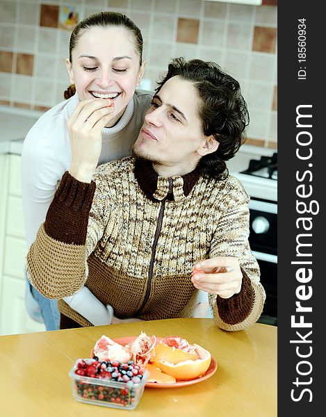 Funny scene of young happy couple playfully eating at kitchen. Funny scene of young happy couple playfully eating at kitchen