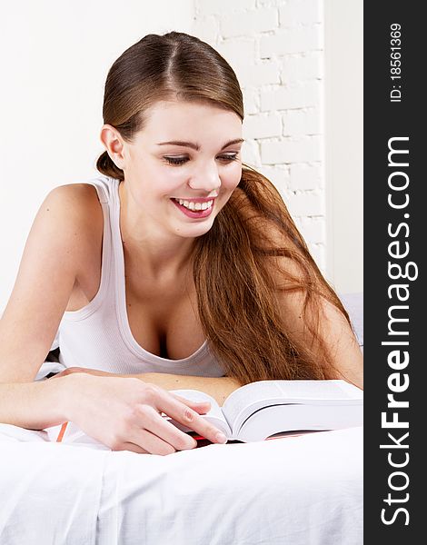 Young beautiful woman reading a book in bed. Young beautiful woman reading a book in bed