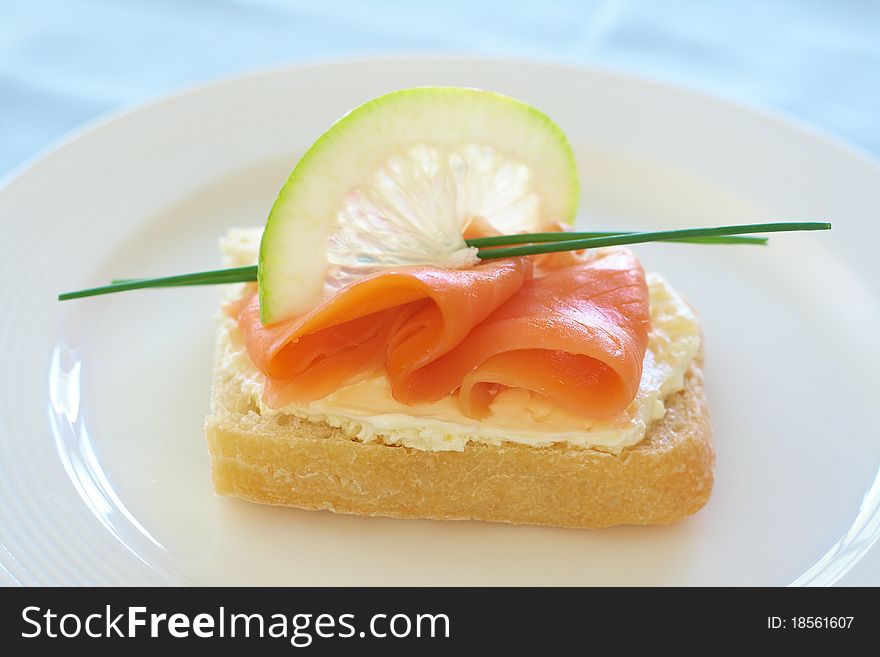 Smoked salmon and cream cheese on white bread with slice of lemon and chives