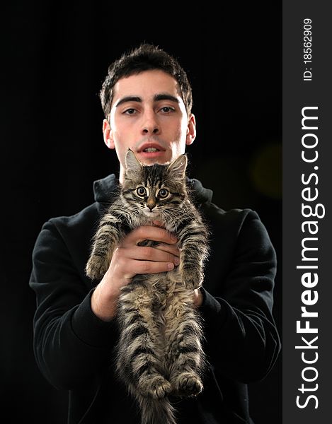 Young  handsome man holding little kitten on dark background. Young  handsome man holding little kitten on dark background