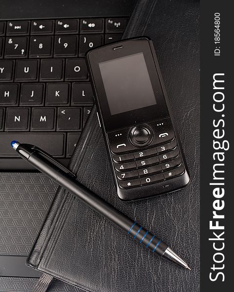 Closeup of black laptop, pen, mobile phone together. Closeup of black laptop, pen, mobile phone together